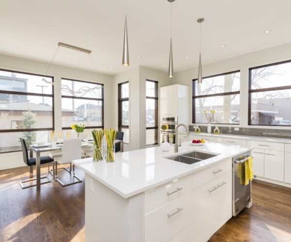 White flat-panel kitchen with cone pendants and quartz island, remodel by VKB Kitchen & Bath